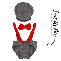 Thumbnail for Crocheted baby outfit with gray diaper cover, red suspenders, and bow tie, accompanied by a gray hat.