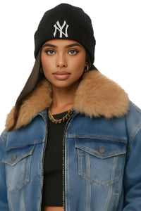 Thumbnail for Woman wearing a black beanie with a logo and a blue denim jacket with a fur-lined collar on a white background