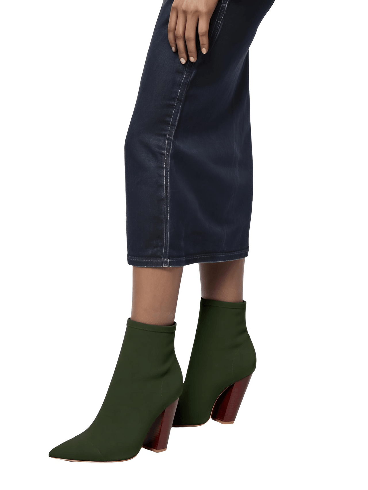 Olive green ankle sock boots with brown soles worn with a dark denim skirt on a white background