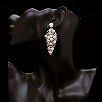 Thumbnail for A pair of bridal earrings featuring a drop design with a cluster of simulated pearls and sparkling rhinestones, with gold plating.