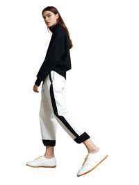Thumbnail for Woman wearing a black top and white pants with black stripes with white sneakers on a white background
