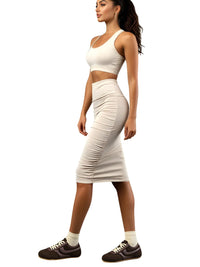 Thumbnail for Woman wearing brown leather sneakers and a white sports bra and skirt set on a white background