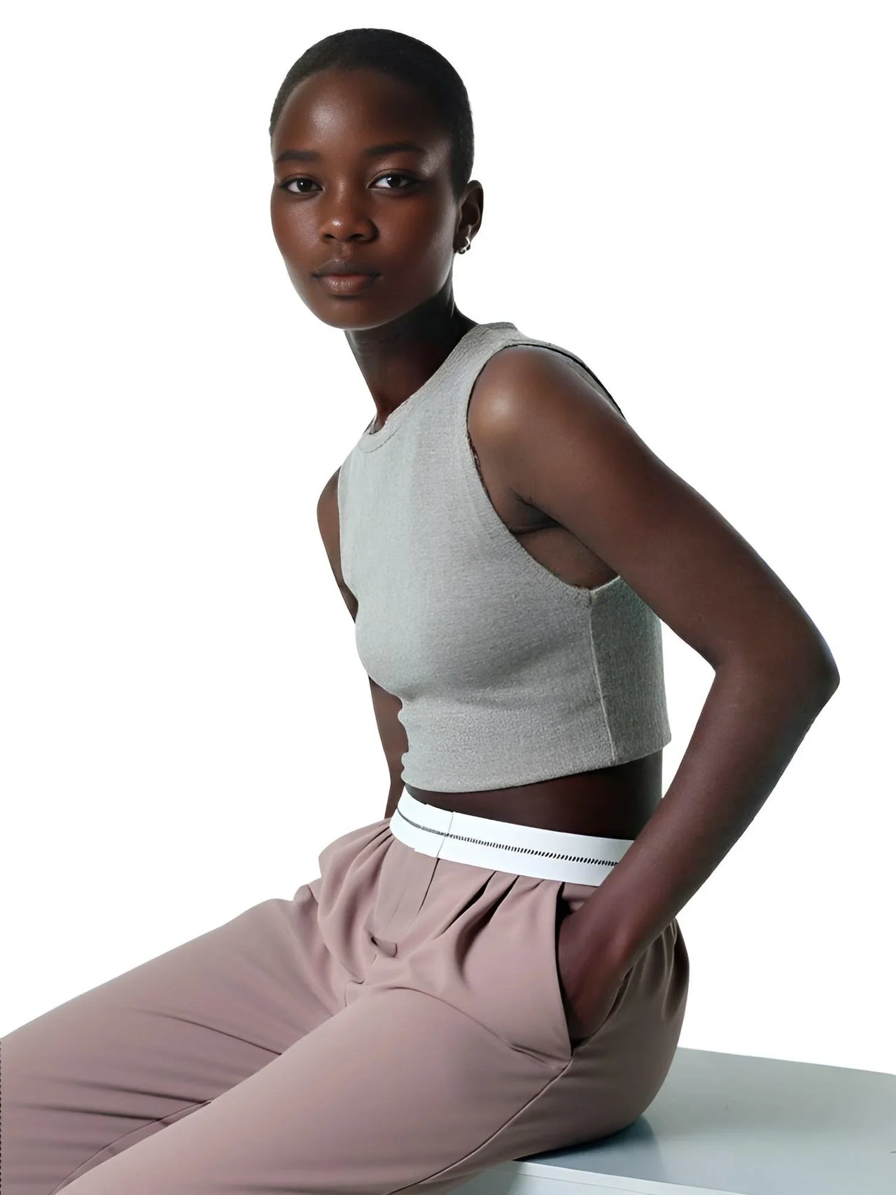 Woman wearing a gray sleeveless top and khaki pants on a white background