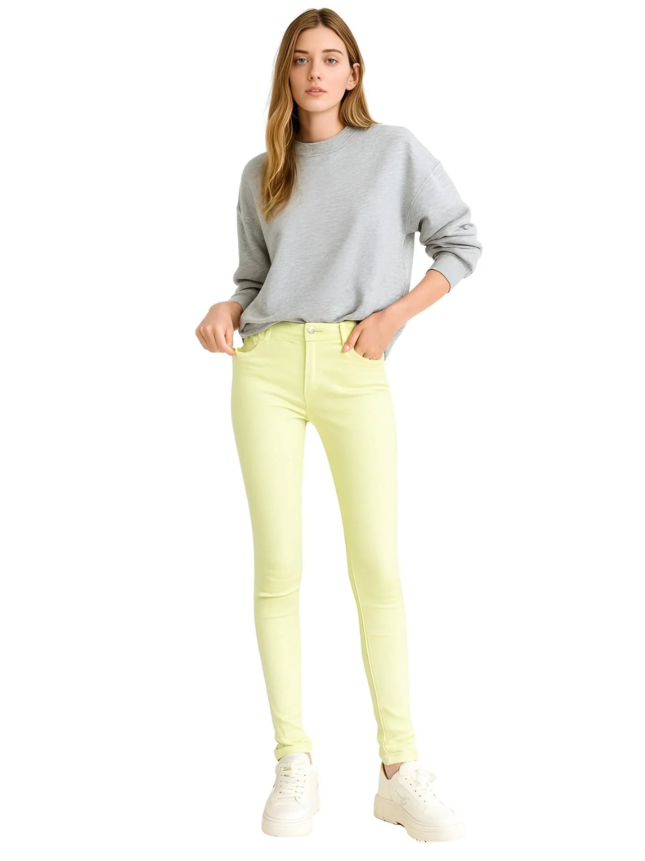 Woman wearing a gray sweatshirt and fruit green skinny jeans on a white background