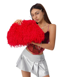 Thumbnail for Woman holding a red feathered clutch bag on a white background