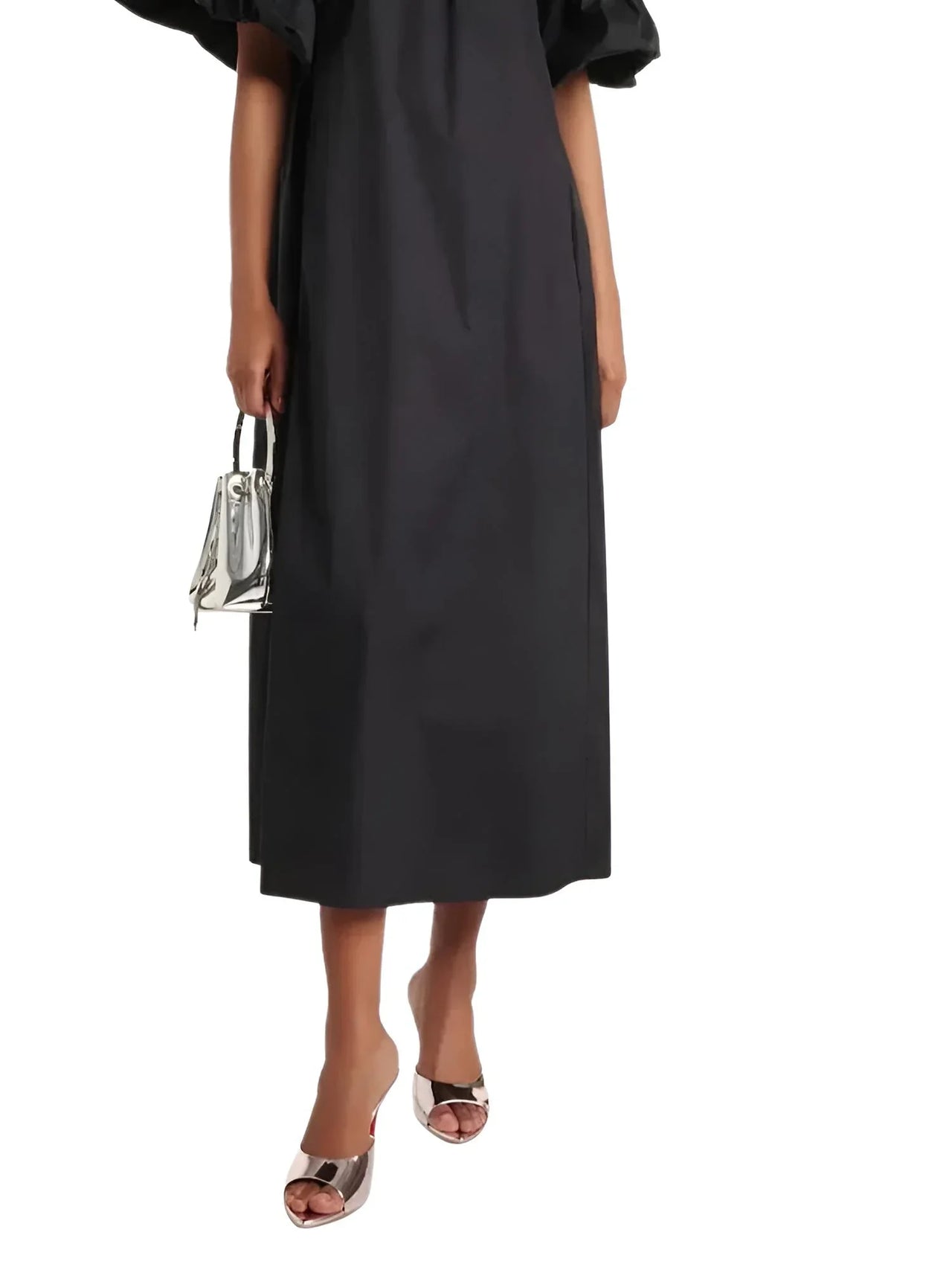 woman wearing a black midi dress wearing gold red sole high heels with a silver purse