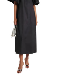 Thumbnail for woman wearing a black midi dress wearing gold red sole high heels with a silver purse