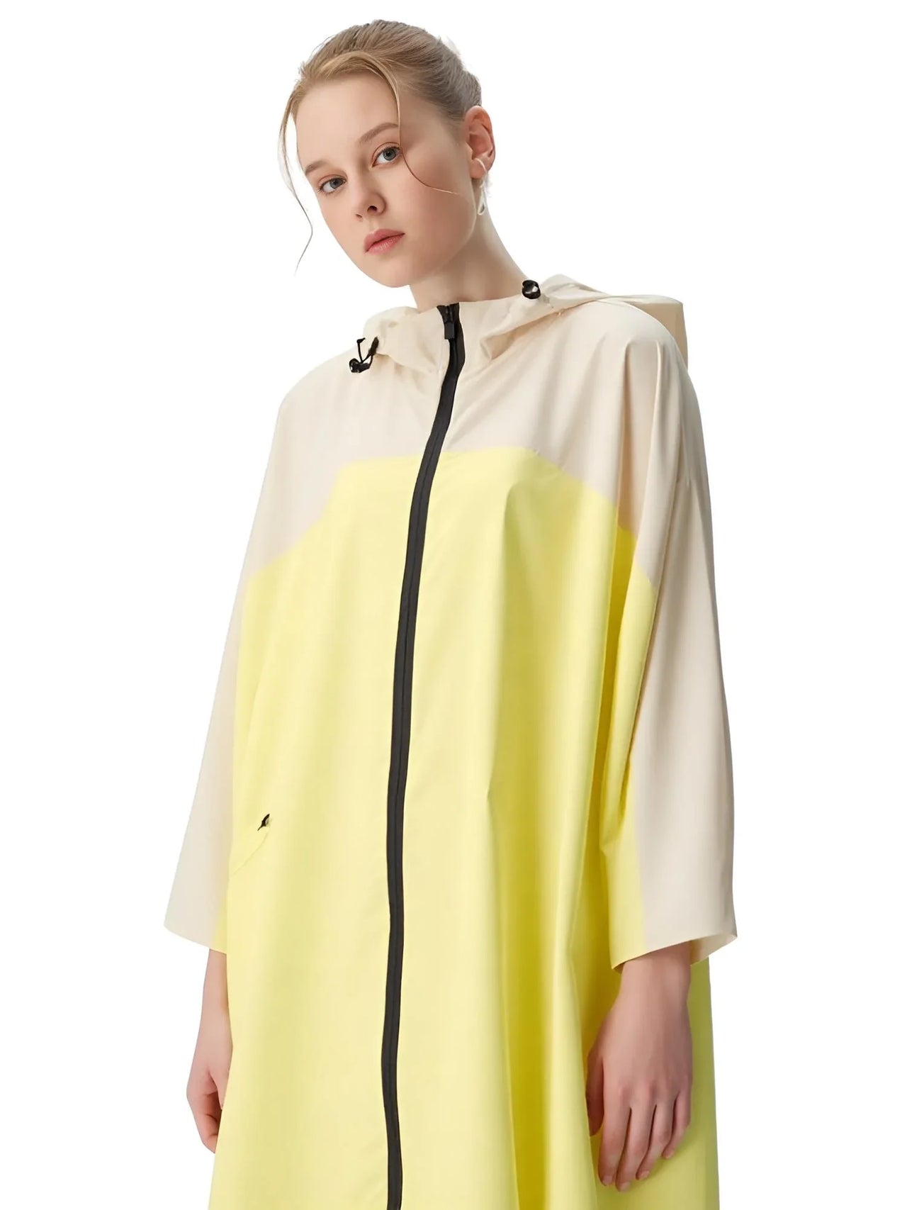 Person wearing a two-tone raincoat with beige and yellow colors on a white background