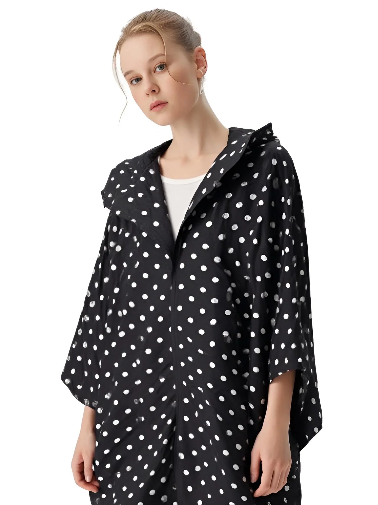 Woman wearing a black raincoat with white polka dots on a white background
