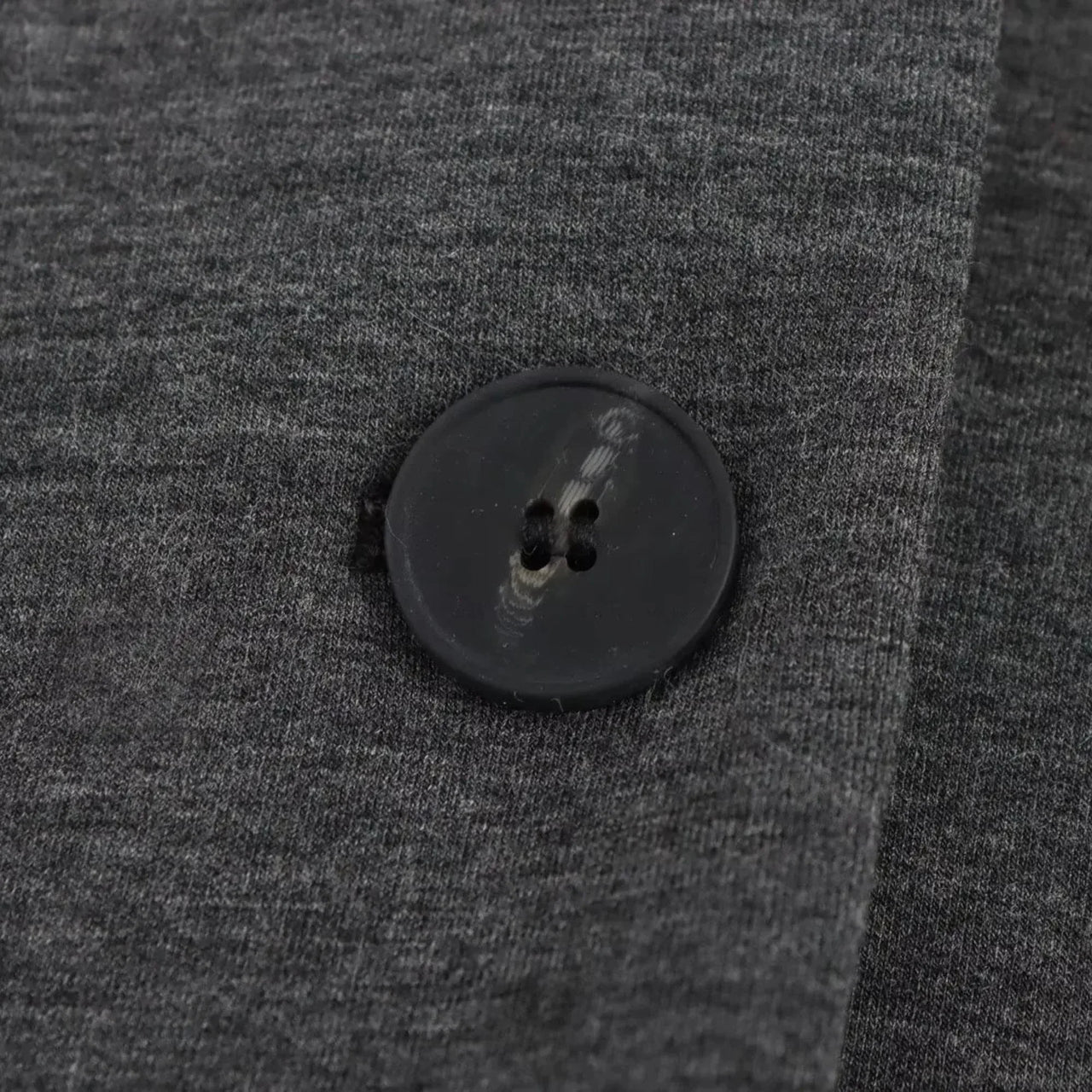 Close-up of a black button on gray fabric