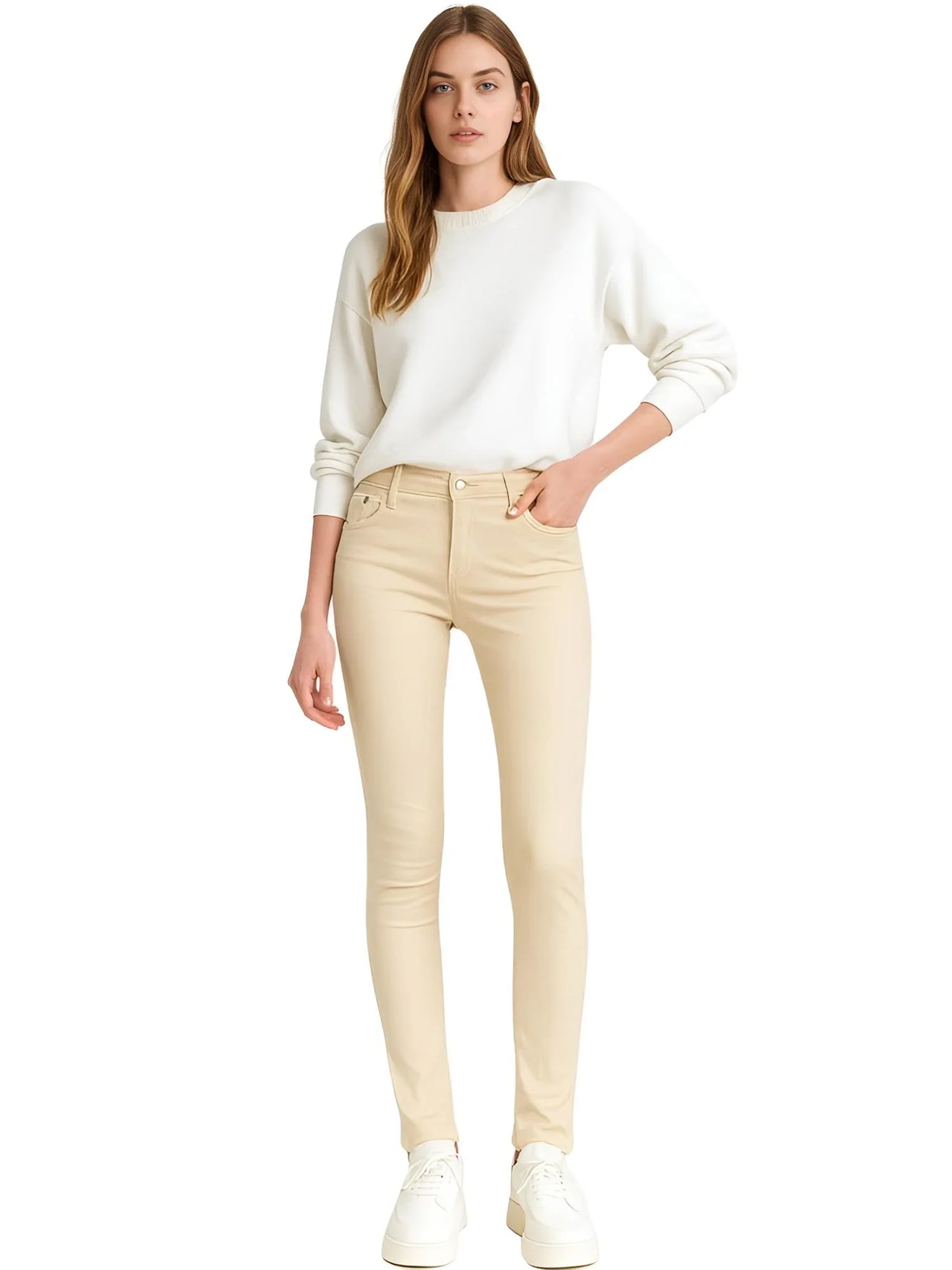 Woman wearing a white sweater and khaki colored skinny jeans on a white background