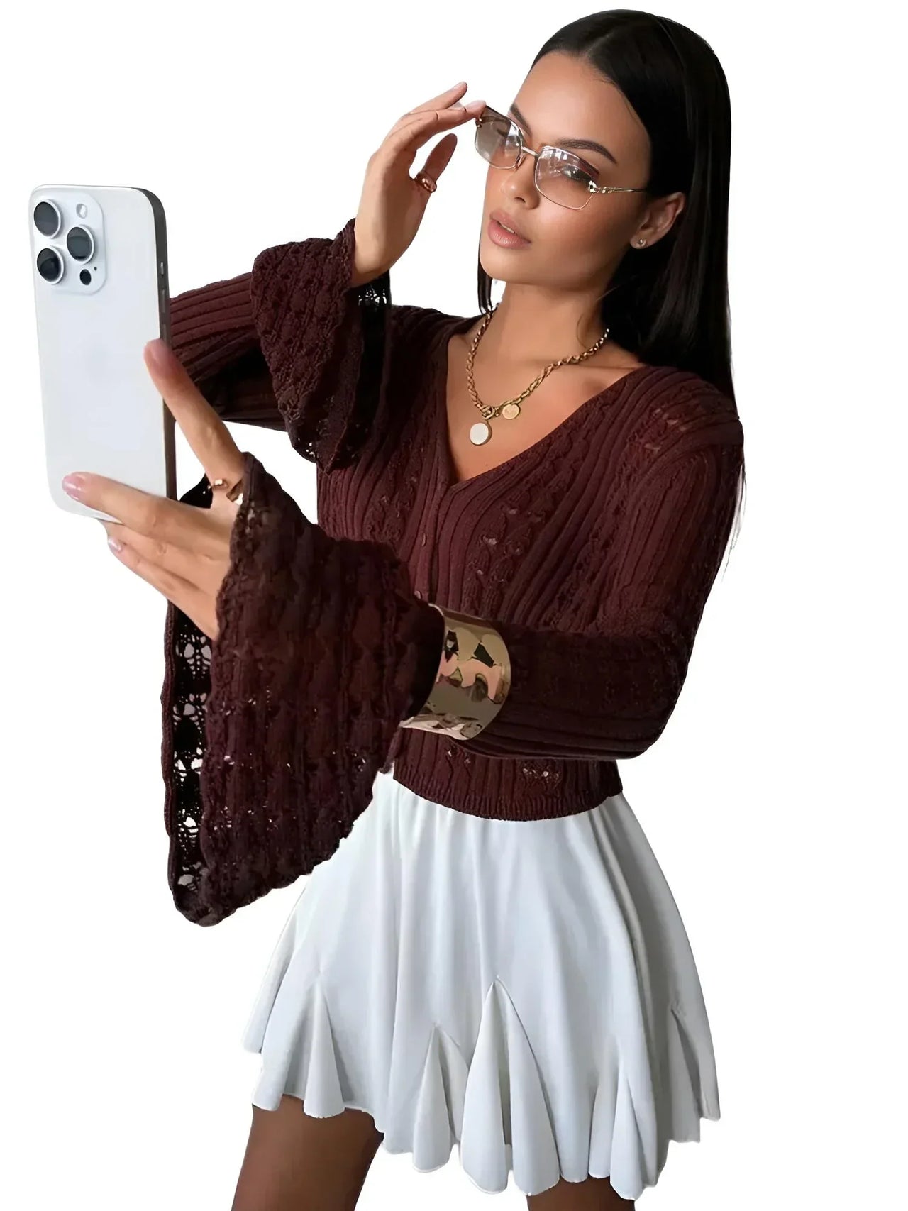 Woman taking a selfie wearing a brown sweater and white skirt on a white background