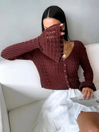 Thumbnail for Woman wearing a brown flare sleeve cardigan and white skirt sitting on a white couch