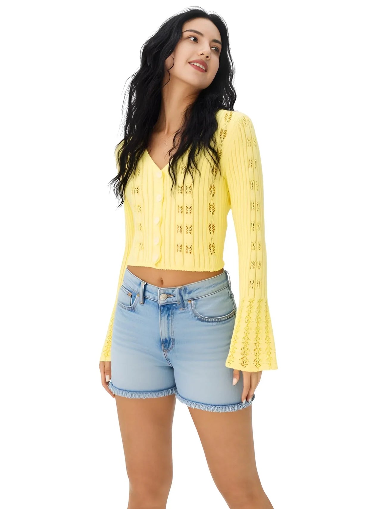 Woman wearing a yellow flare sleeve cardigan and denim shorts on a white background