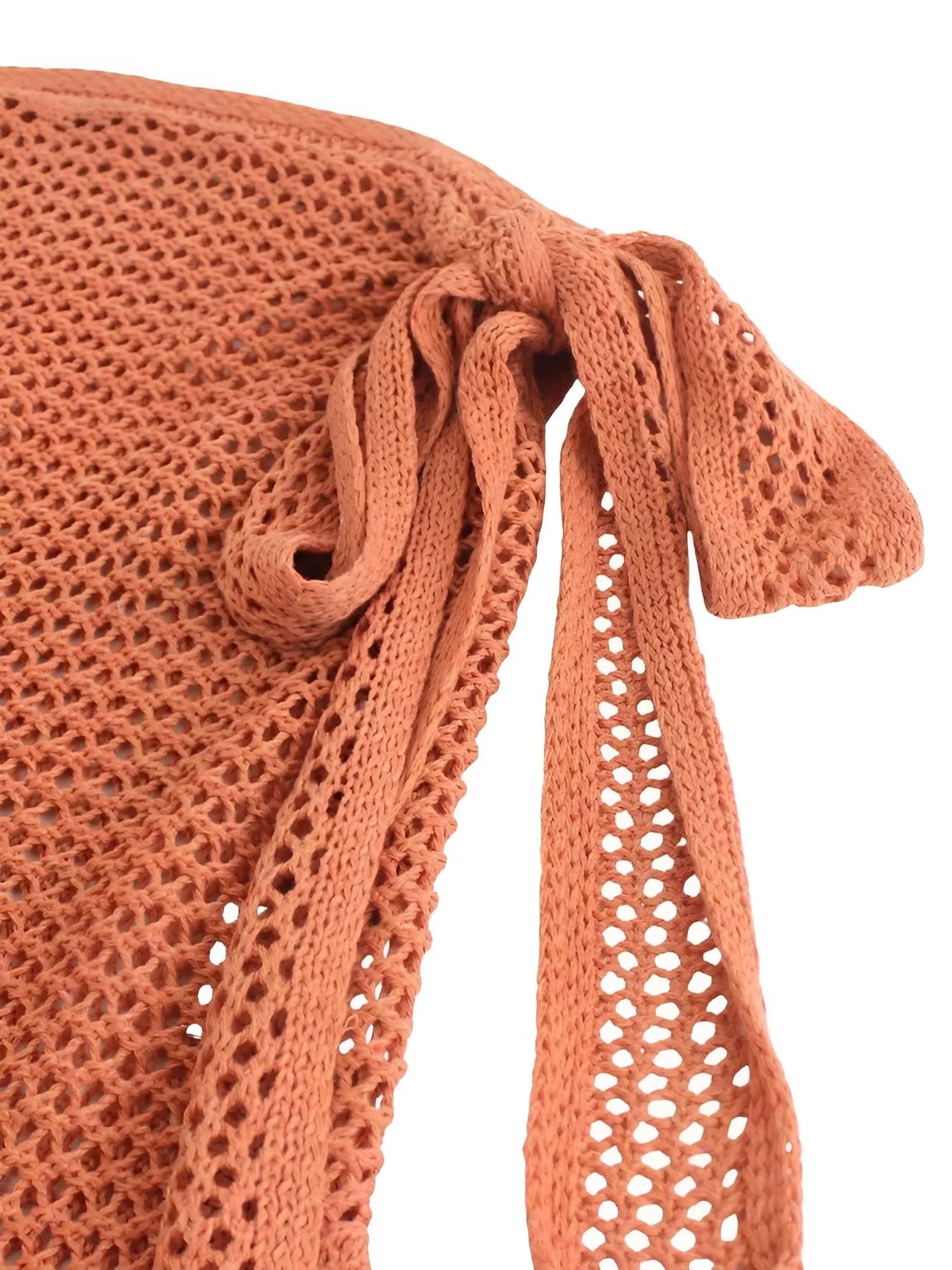 Close-up of a terracotta-colored knitted top with a bow detail on a white background