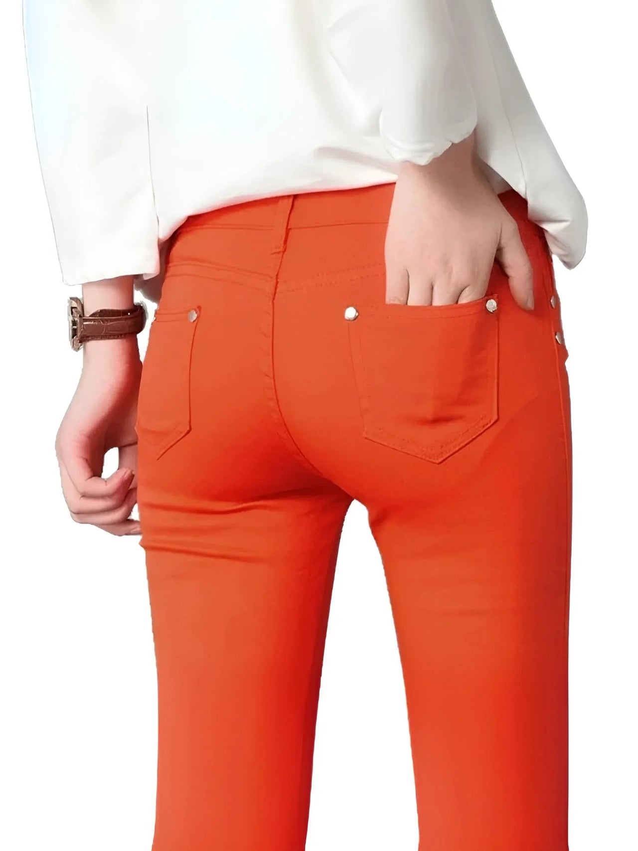 Person wearing bright orange skinny jeans with a white shirt on a white background