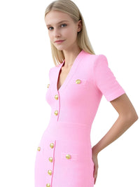 Thumbnail for Woman wearing a pink dress with gold buttons on a white background