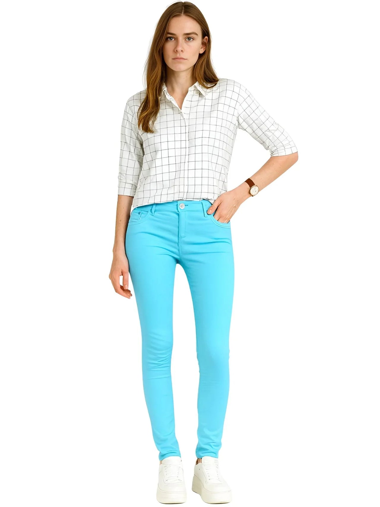 Woman wearing a checkered shirt and bright blue skinny jeans on a white background