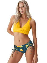 Thumbnail for Woman wearing a yellow top and green lemon bottom bikini on a white background