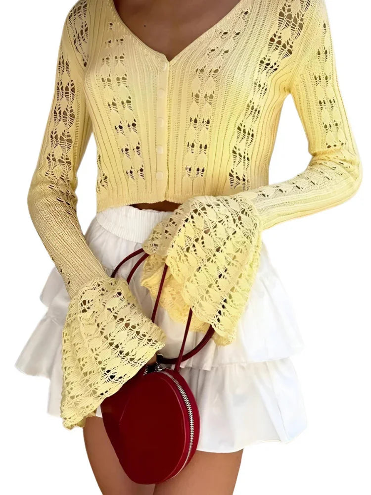 Woman wearing a yellow flare sleeve cardigan and white skirt with a red handbag on a white background