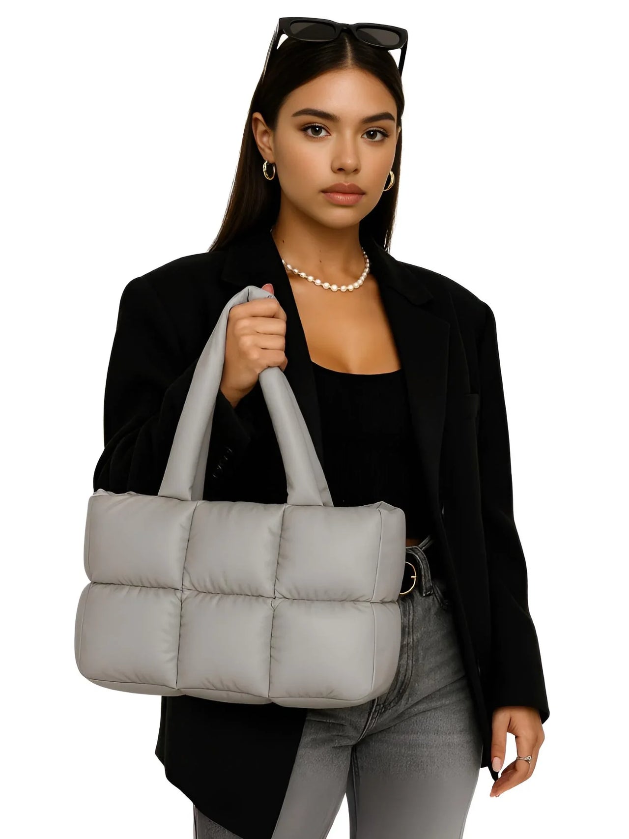 Woman holding a gray puffer bag against a white background