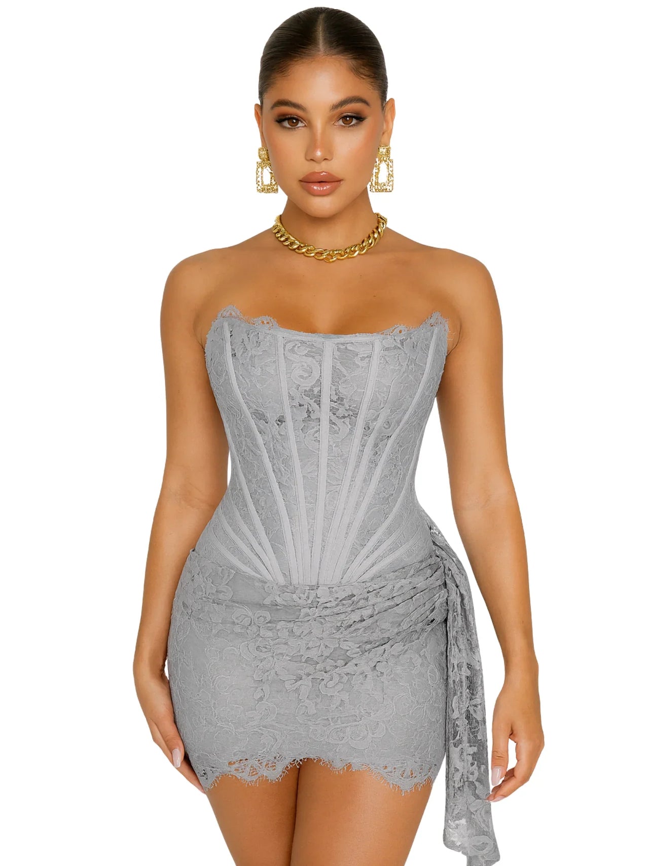 Woman wearing a strapless gray lace dress with gold jewelry on a white background
