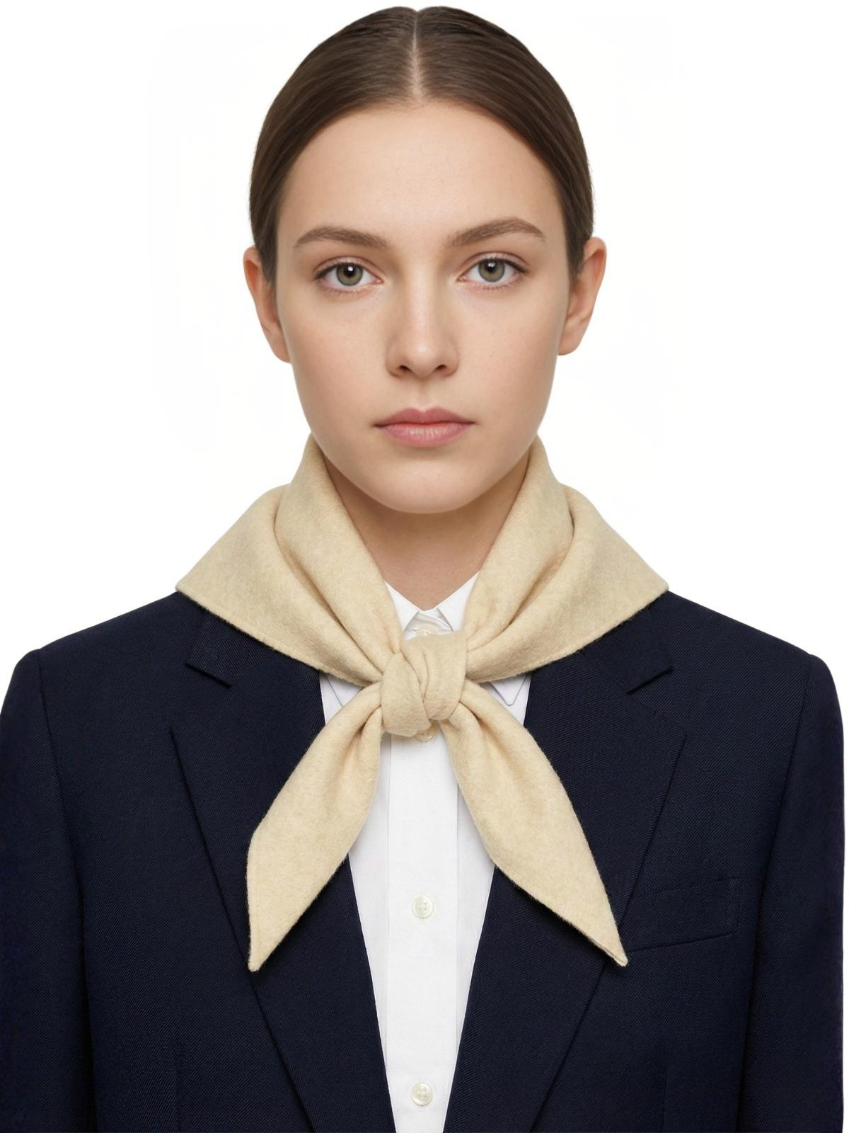 Woman wearing a beige scarf and navy blazer on a white background