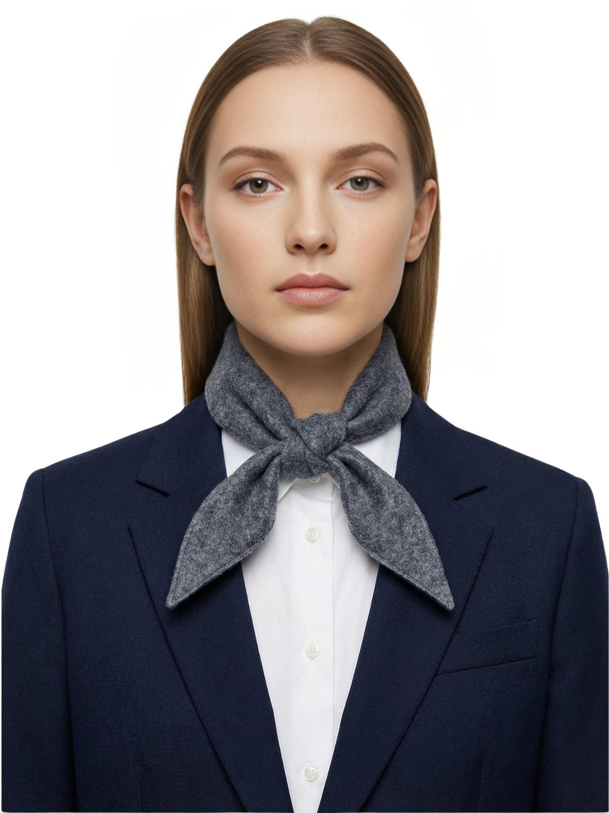 Woman wearing a navy blazer and white shirt with a gray wool scarf around her neck on a white background