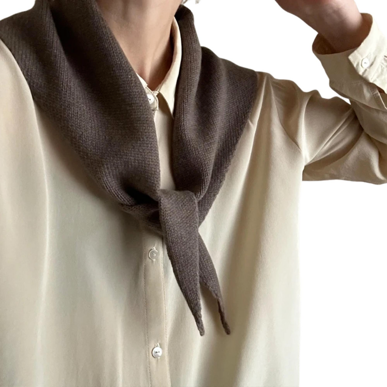 Person wearing a brown wool scarf over a beige shirt on a white background