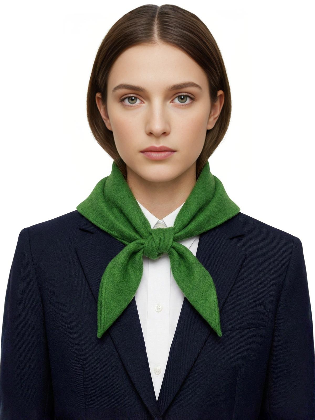 Woman wearing a green wool scarf and navy blazer on a white background