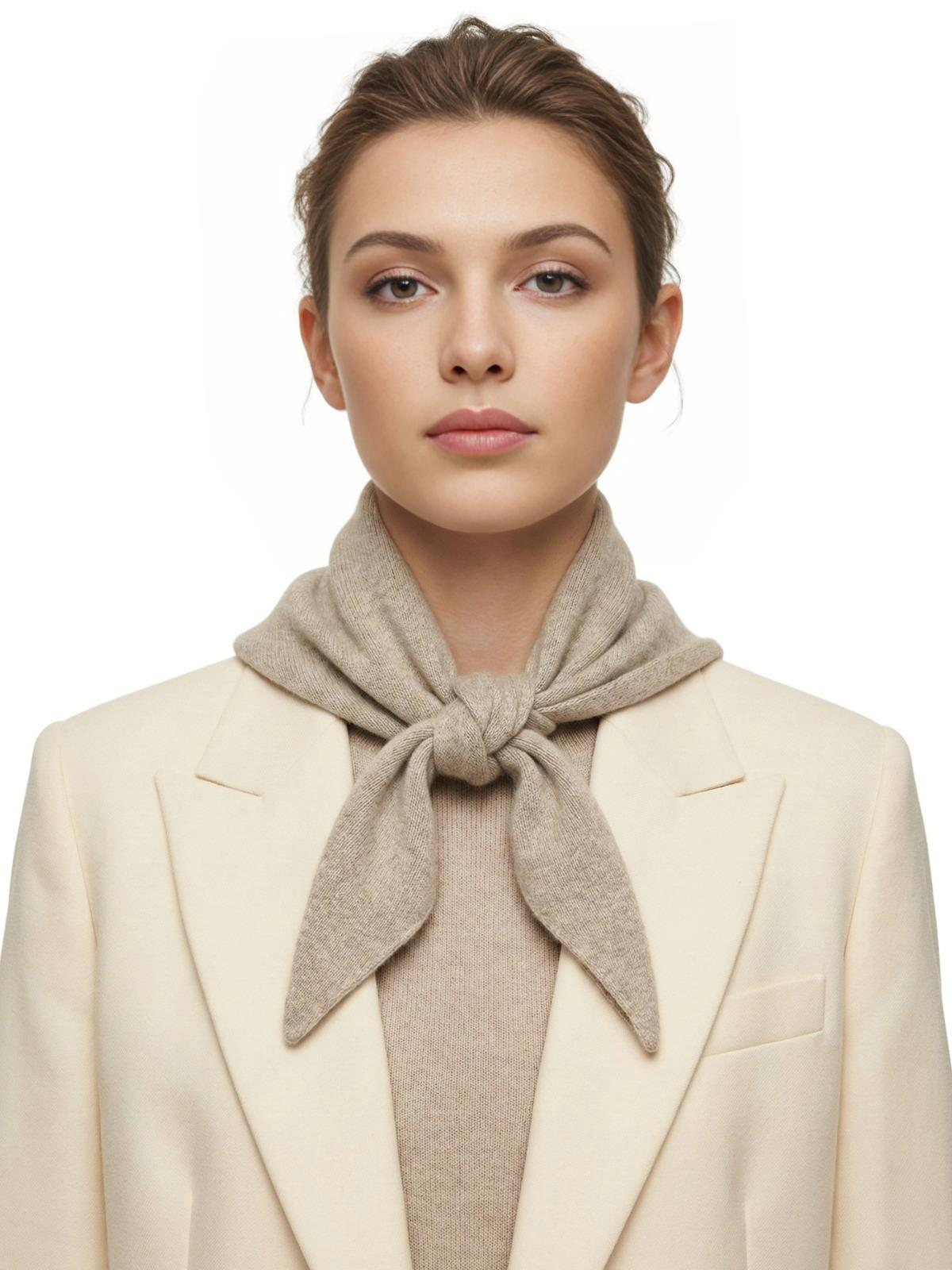 Woman wearing a khaki wool scarf and cream blazer on a white background