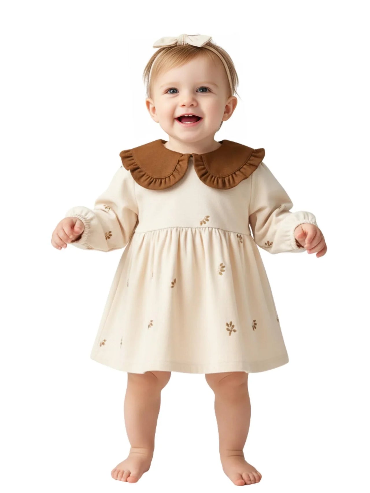 Baby wearing a beige dress with a brown collar on a white background