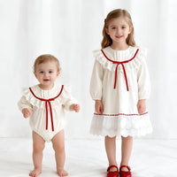 Thumbnail for Two children wearing white outfits with red trim on a white background