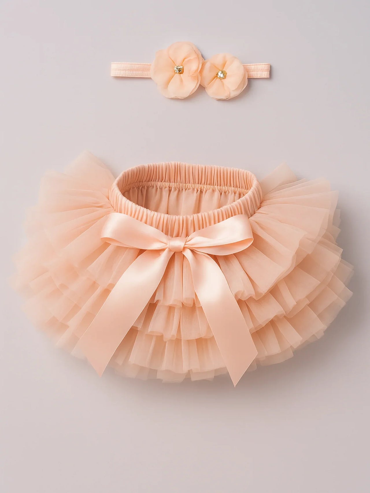 Peach tutu skirt with a bow and matching headband on a light gray background