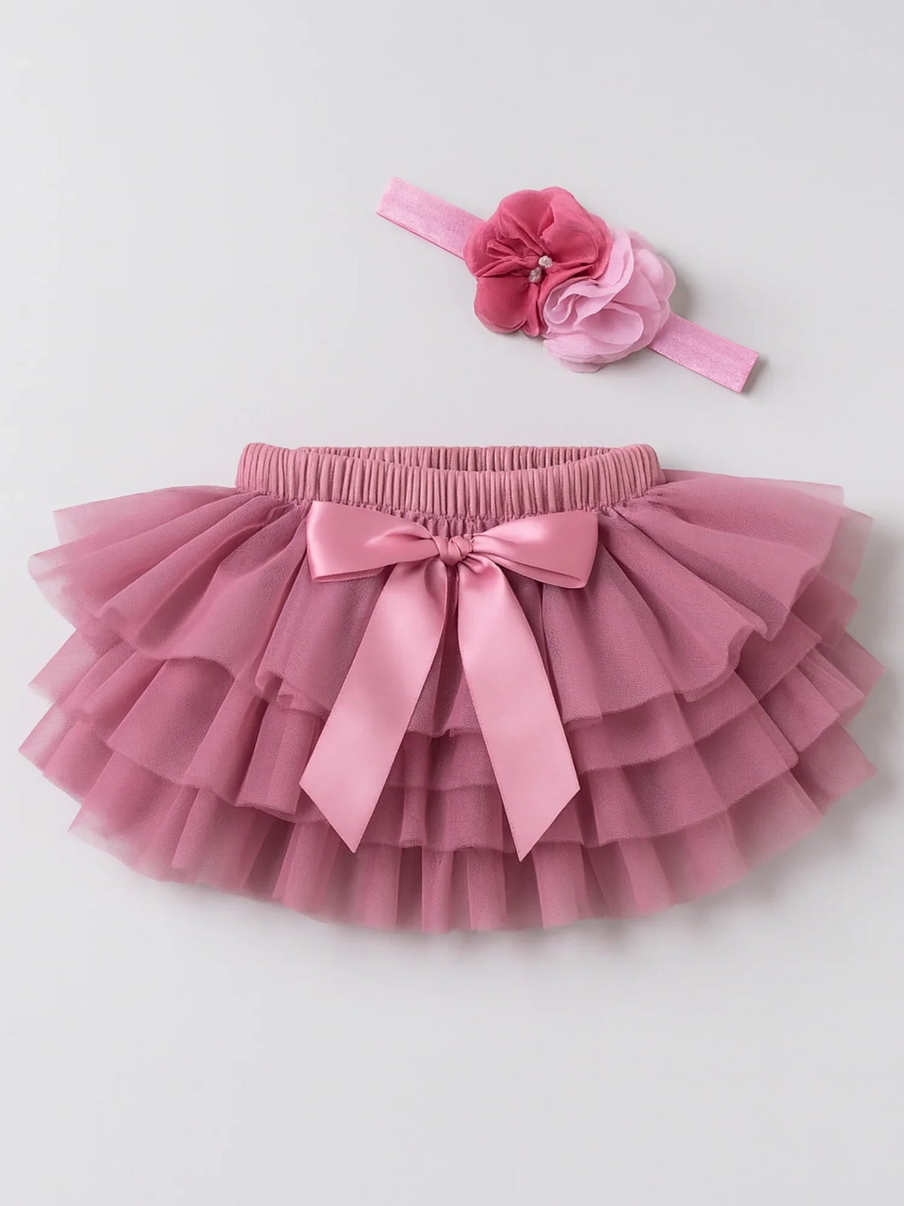 Pink tutu skirt with a matching headband on a light gray background