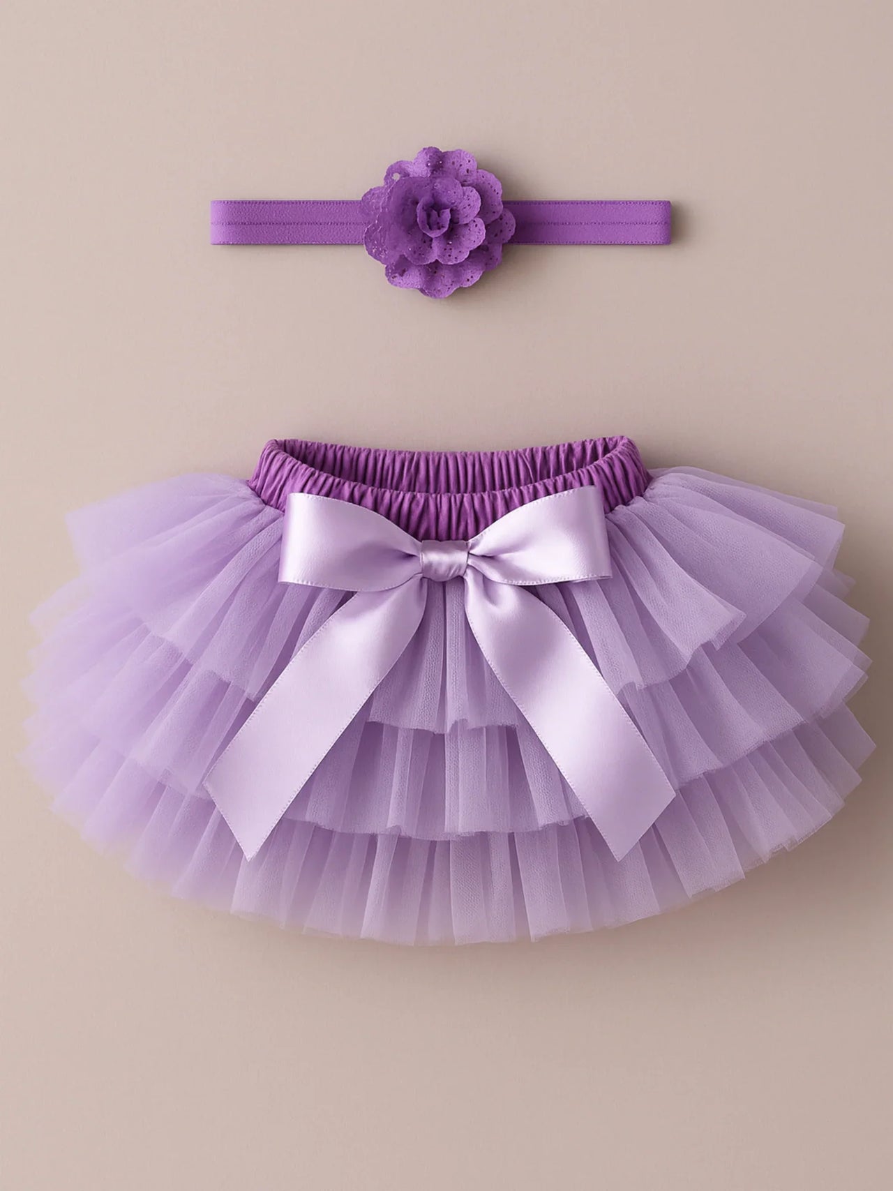Purple tutu skirt with a bow and matching headband on a beige background