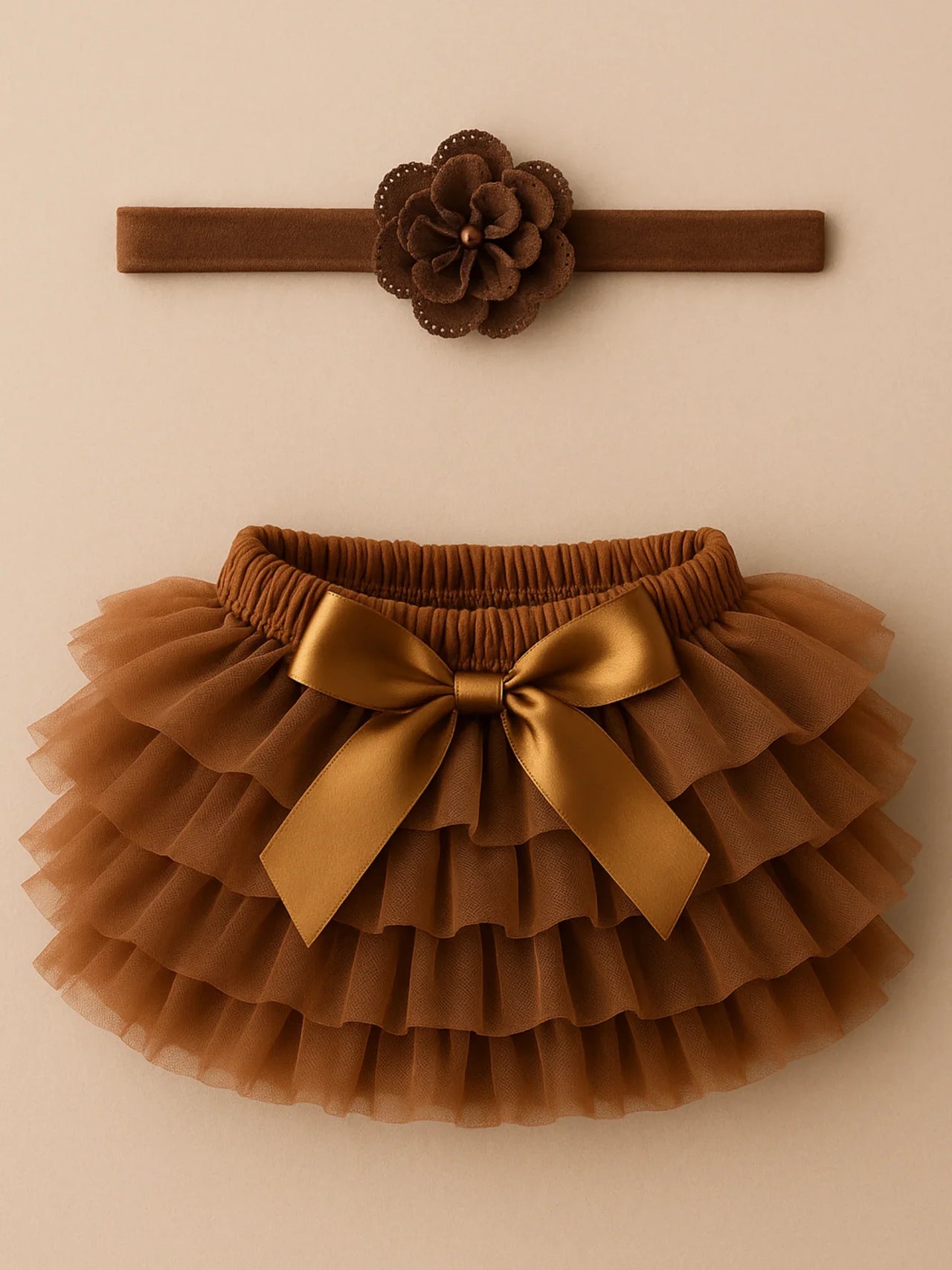 Brown tutu skirt with gold bow and matching headband on a beige background