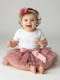 Thumbnail for Baby wearing a white onesie with a pink tutu and headband on a light gray background