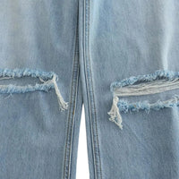 Thumbnail for Close-up of a light blue denim jeans with ripped frayed edges on a white background