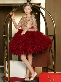 Thumbnail for Young girl in a glamorous dress with a red skirt and gold top, standing in a stylish interior setting.