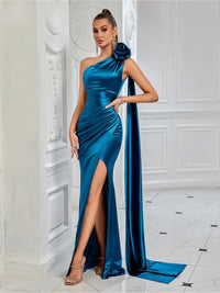 Thumbnail for Woman wearing a blue satin one-shoulder gown with a high slit in a white room.
