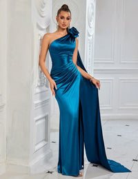 Thumbnail for Woman in a blue one-shoulder satin gown standing in an elegant interior setting.
