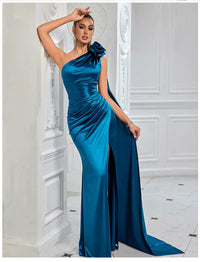 Thumbnail for Woman wearing a blue satin one-shoulder gown with a large flower detail in an elegant interior setting.