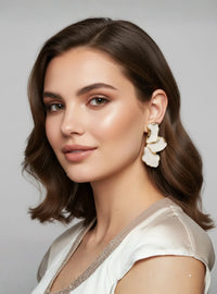 Thumbnail for Woman wearing a white blouse with floral earrings against a neutral background