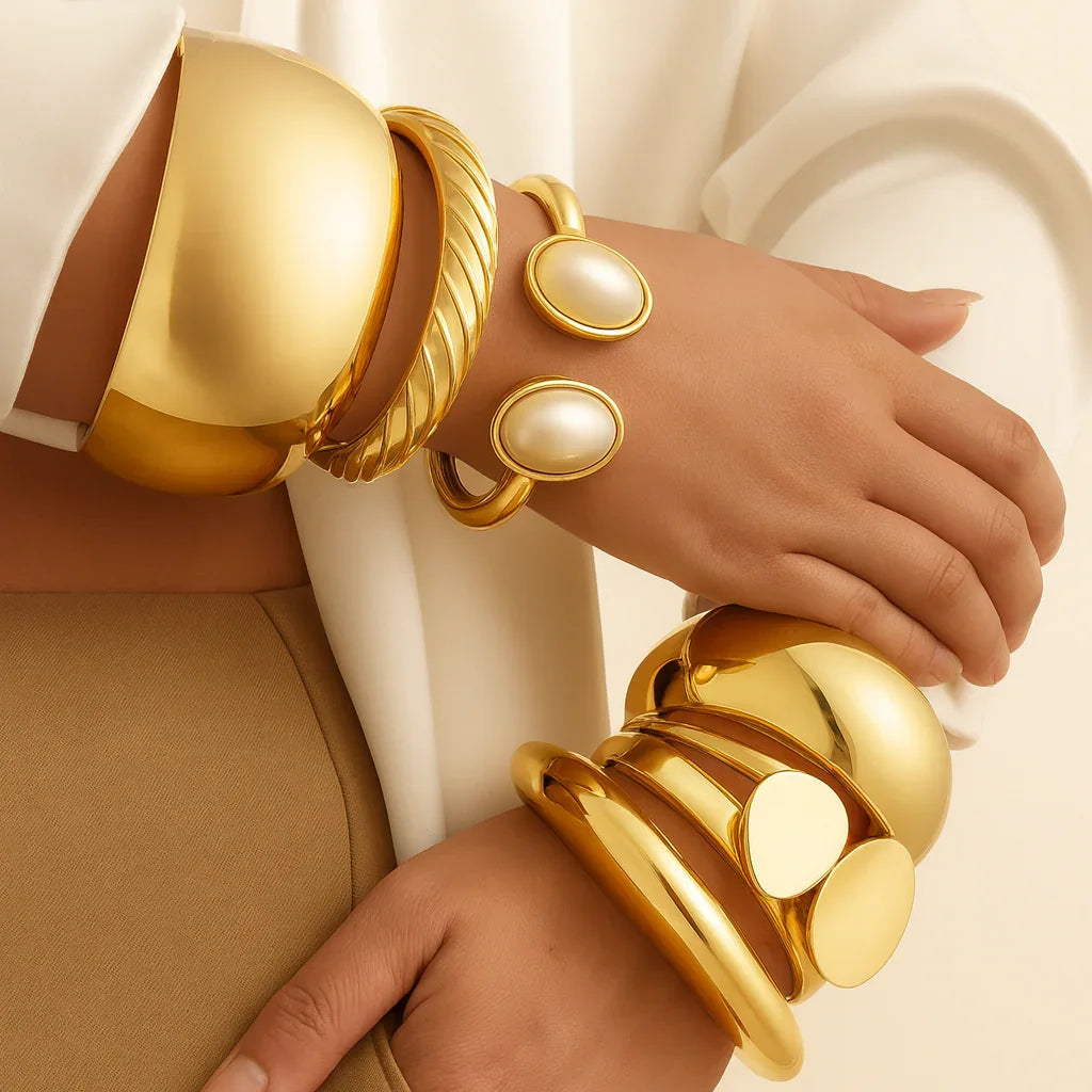 Gold bracelets with pearl-like stones on a neutral background
