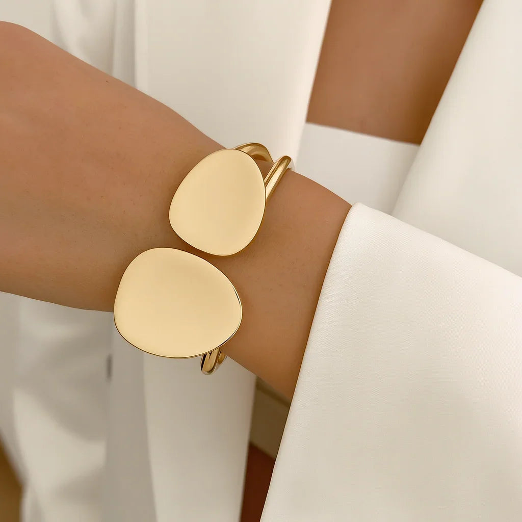 Gold bracelet on a wrist with a blurred white background