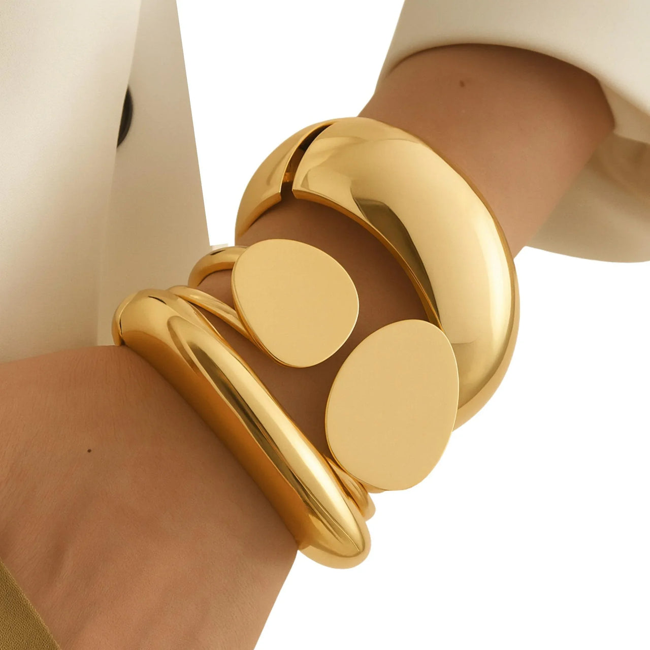 Gold bracelet on a wrist with a plain background
