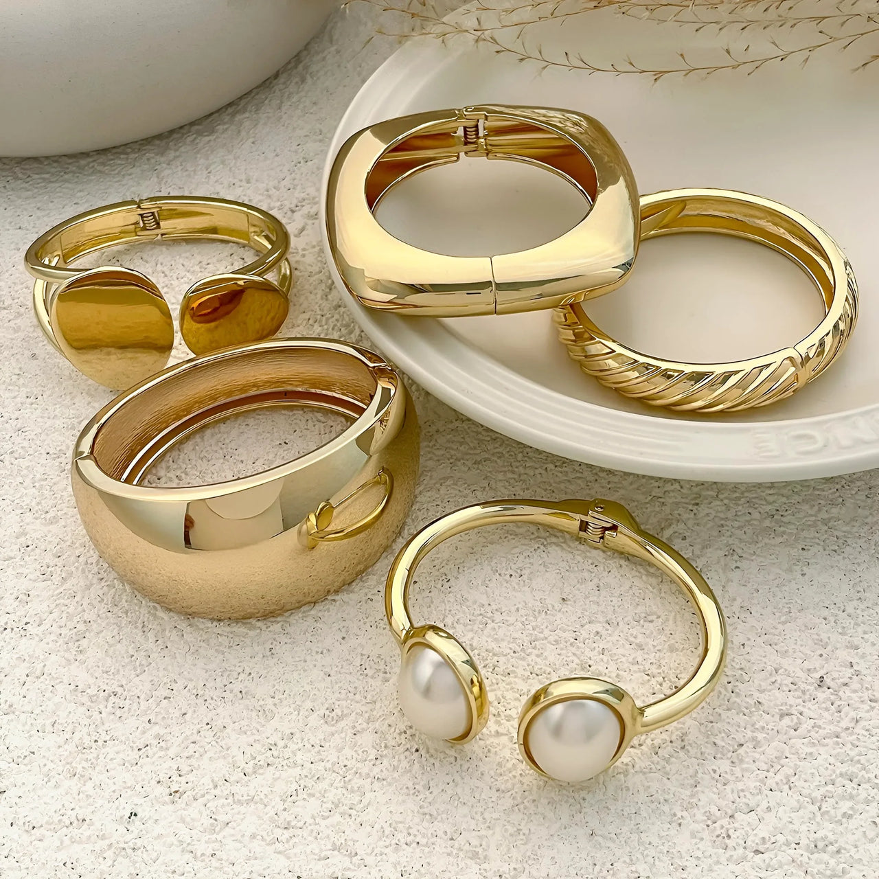 Gold bracelets with pearl accents on a textured surface