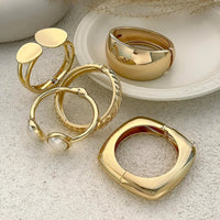 Thumbnail for Gold rings on a textured surface with a white dish in the background