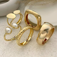 Thumbnail for Set of gold rings with pearls on a textured surface